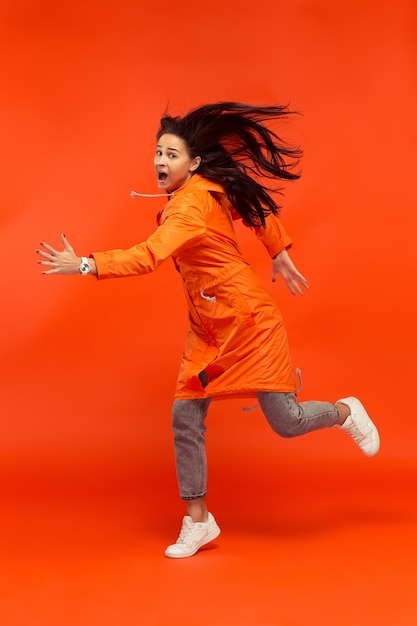 The young girl posing at  in autumn jacket isolated on red