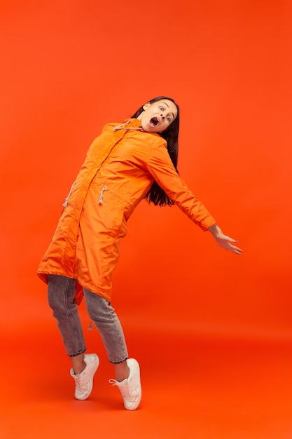 The young girl posing at  in autumn jacket isolated on red