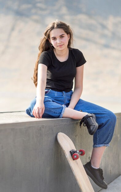 Young girl posing next to skateboard outside