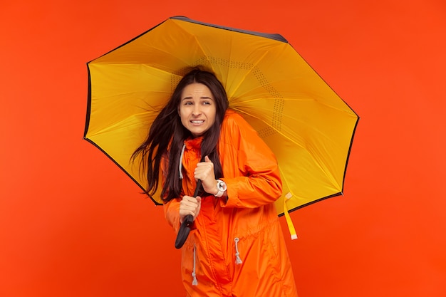 young girl posing at studio in autumn jacket isolated on red