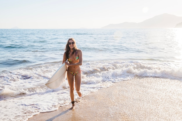 Молодая девушка позирует с доской для серфинга