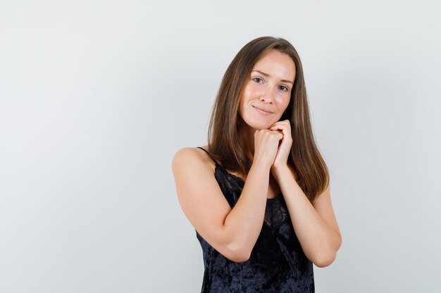 Young girl propping chin on hands in black singlet and looking delicate