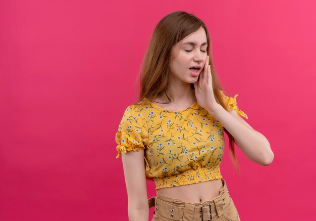 Young girl putting hand near mouth and whispering on isolated pink wall with copy space