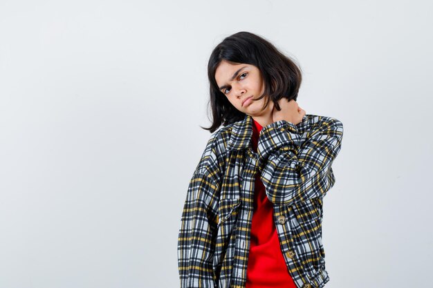 Young girl putting hand on shoulder in checked shirt and red t-shirt and looking angry. front view.