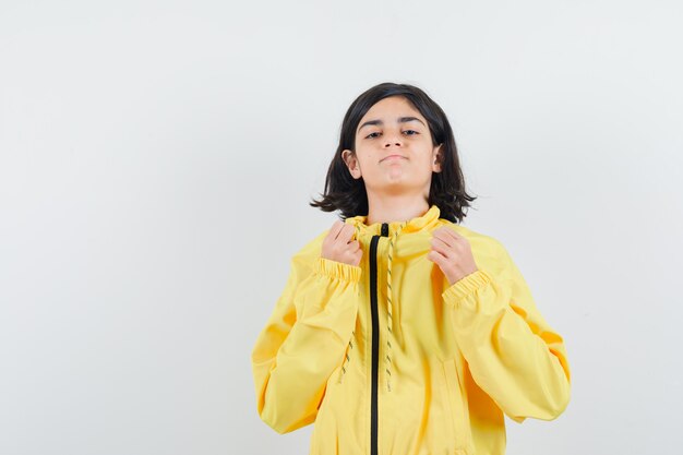 黄色のボンバージャケットのジャケットに手を置いて、自信を持って見える少女。