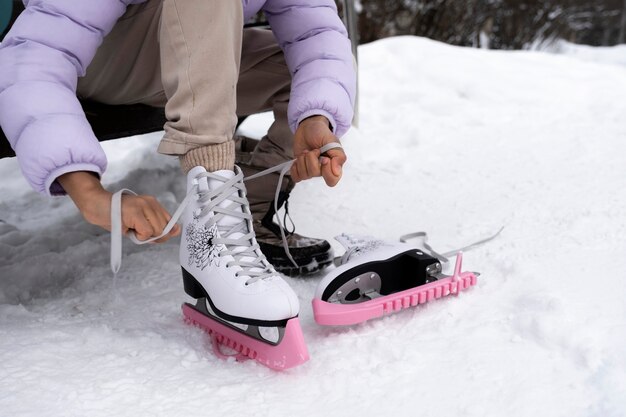 Young girl putting on her ice skates outdoors in winter