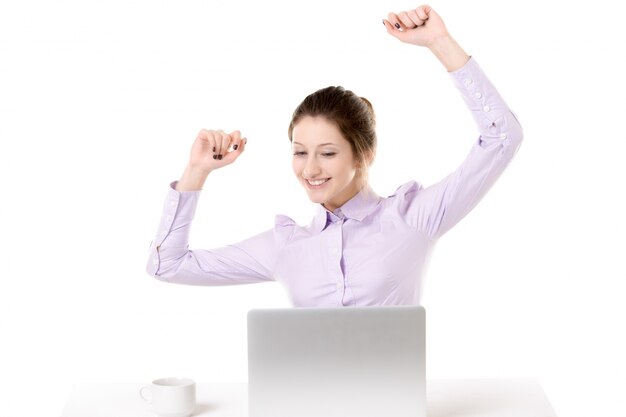 Young girl raising arms with happy expression in front of laptop