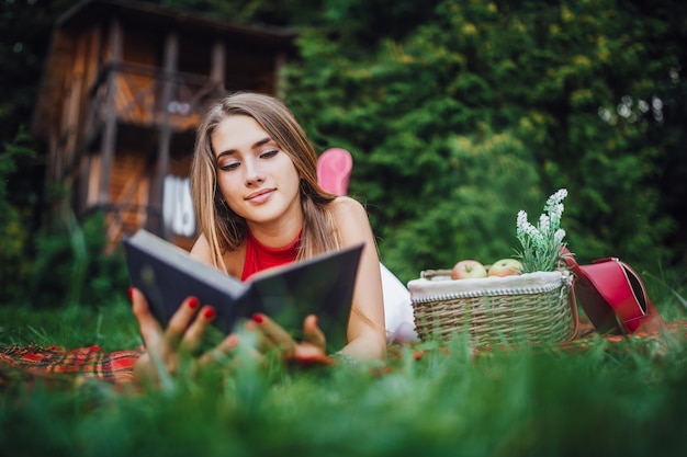 공원에서 잔디에 과일과 함께 책을 읽는 어린 소녀