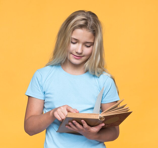 黄色の背景で読んでいる若い女の子