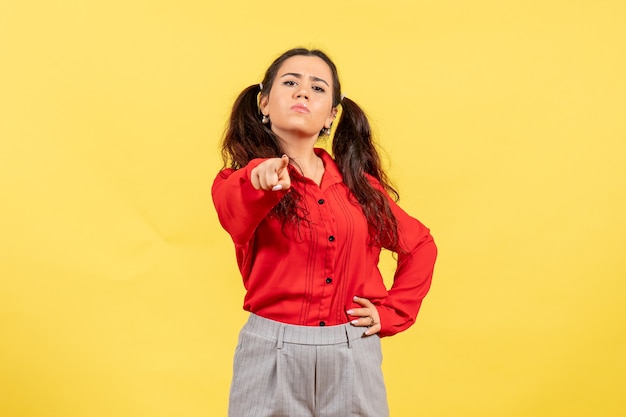 young girl in red blouse angrily pointing on yellow