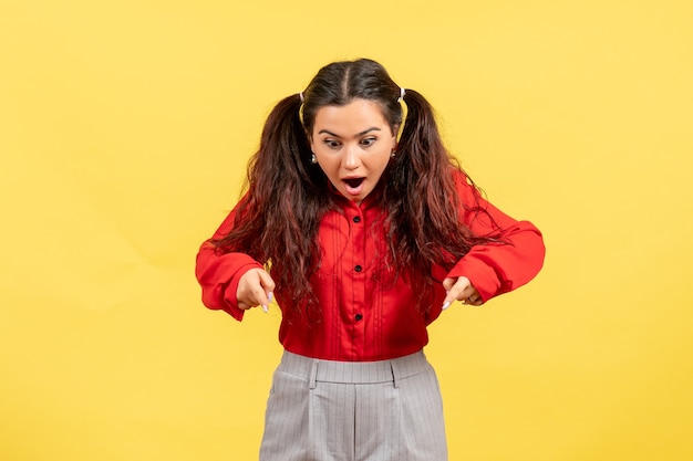 young girl in red blouse looking with shocked face on yellow