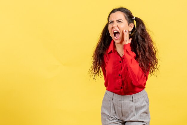 young girl in red blouse loudly calling someone on yellow