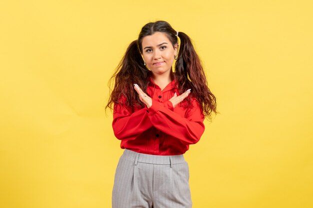 young girl in red blouse posing on yellow