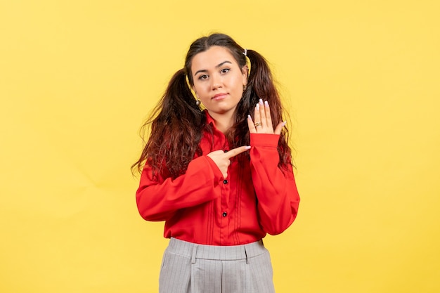 Free photo young girl in red blouse posing on yellow