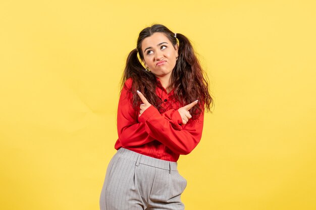 young girl in red blouse posing on yellow