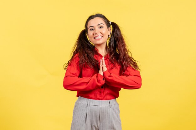 young girl in red blouse smiling on yellow