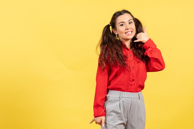 young girl in red blouse smiling on yellow