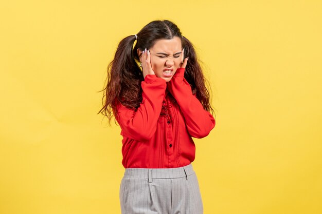 young girl in red blouse suffering from headache on yellow