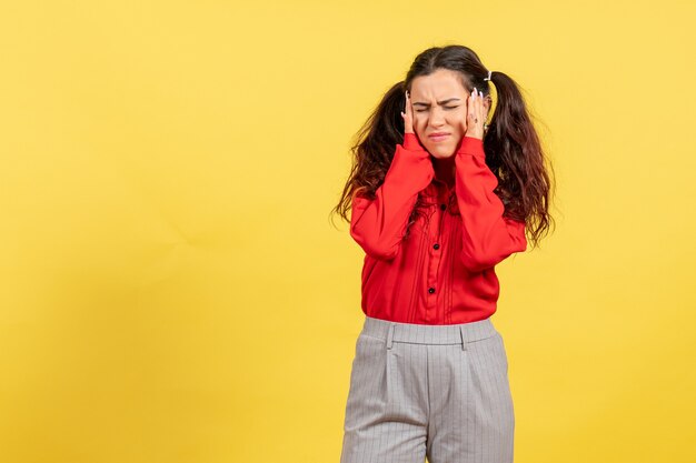 young girl in red blouse suffering from headache on yellow