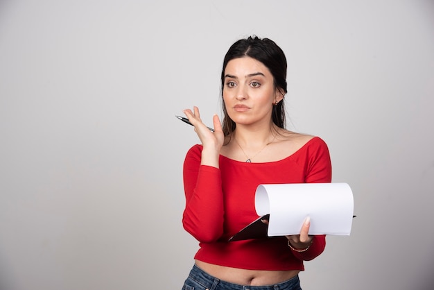 Young girl in red blouse with clipboard looking at somewhere.