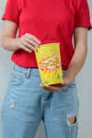 Free photo young girl in red shirt holding a box of popcorns