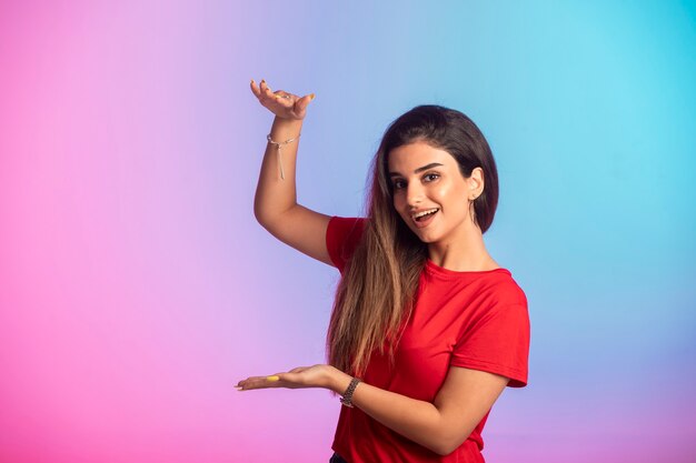 Young girl in red shirt showing dimensions.