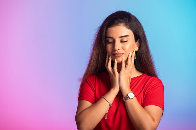 Young girl in red shirt touching her face