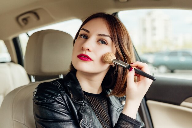 Young girl retouching her makeup while stopped in the traffic