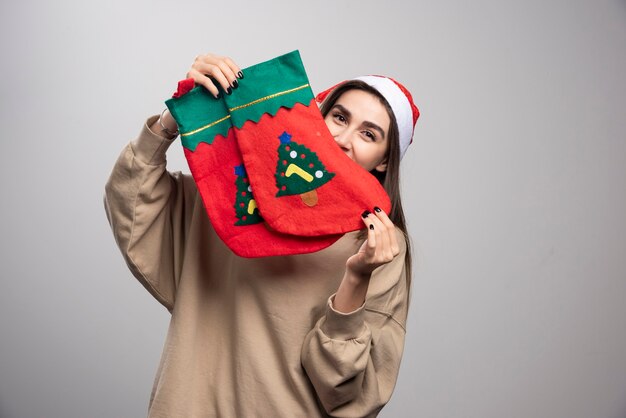 Free photo young girl in santa's hat holding two christmas socks .