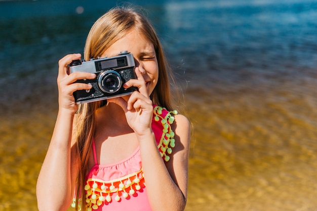 Young girl shooting on camera against background of sea 