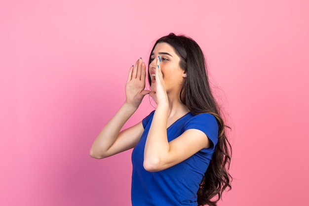 Young girl shouted for someone on pink background High quality photo