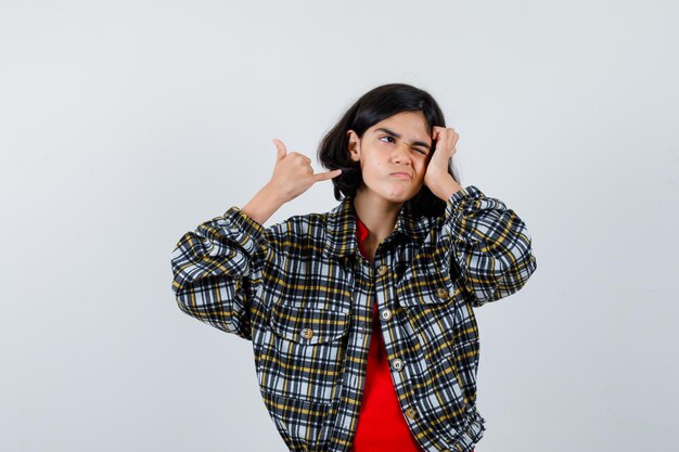 チェックのシャツと赤いTシャツで私をジェスチャーと呼んでいる若い女の子がかわいく見える、正面図。