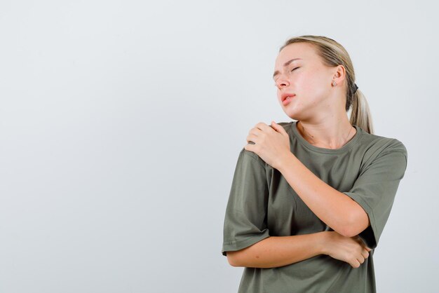 Young girl showing her left shoulder hurting on white background