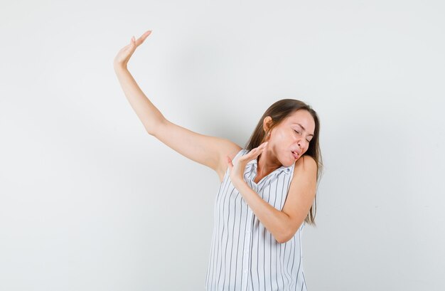 Tシャツで頭を回し、うんざりしているように見える間、停止ジェスチャーを示す若い女の子。正面図。