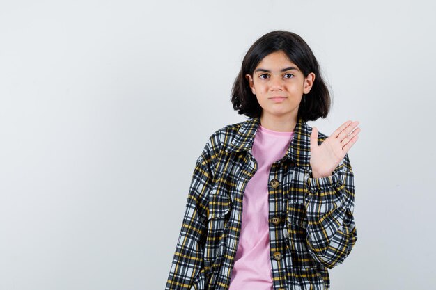 Free photo young girl showing stop sign in checked shirt and pink t-shirt and looking pretty , front view.