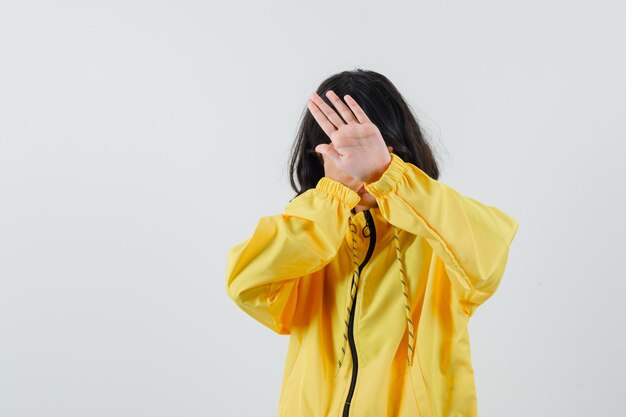 노란색 폭격기 재킷에 정지 신호를 표시하고 심각한 찾고 어린 소녀
