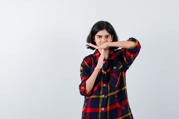 Young girl showing time-break gesture in checked shirt and looking serious , front view.