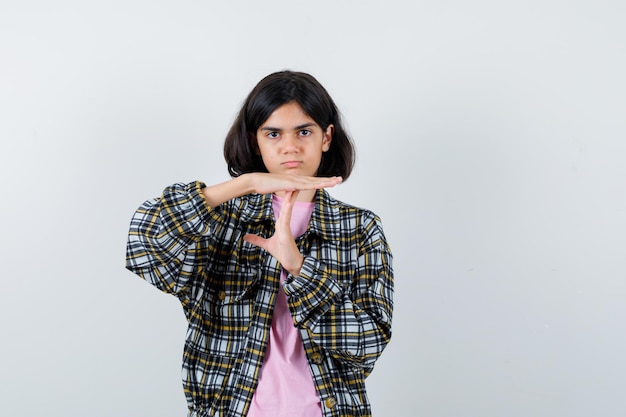 Free photo young girl showing time-break sign in checked shirt and pink t-shirt and looking serious.