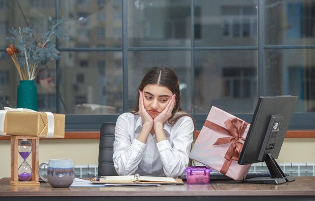 Young girl sitting art the desk around her birthday gifts