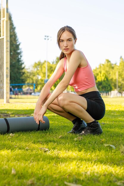 彼女のスポーツマットの横に座って、カメラを見ている若い女の子