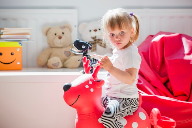 Young girl sitting on deer toy