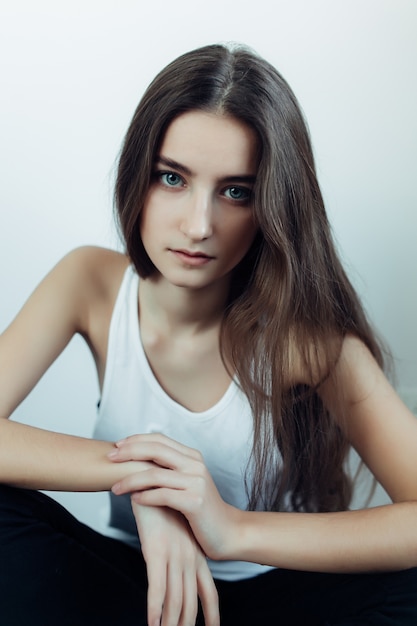 Young girl sitting on the floor with one hand over another