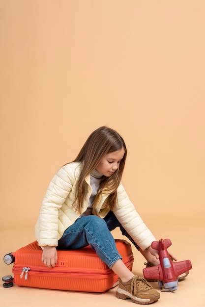 Young girl sitting on luggage for traveling