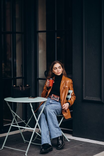 カフェの外に座ってコーヒーを飲む若い女の子