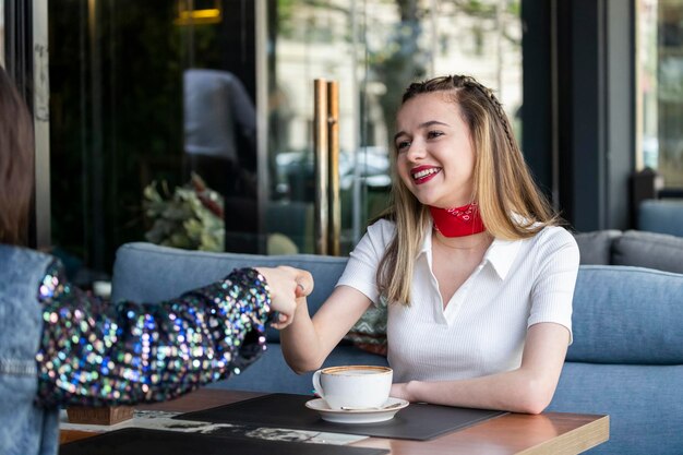 Young girl sitting at the restaurant and shaking her friend39s hand