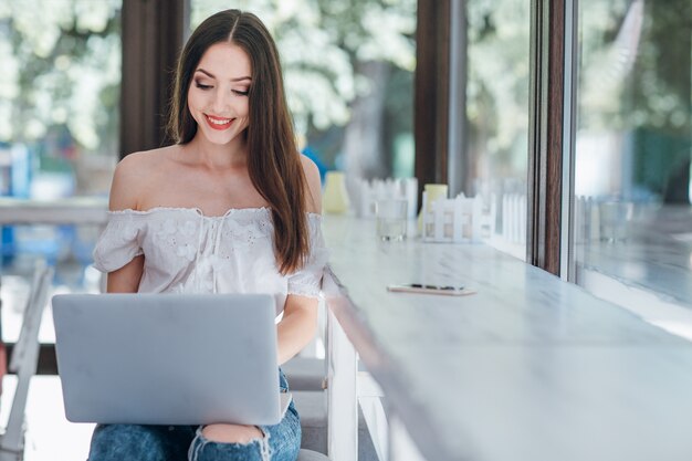 Young girl smiling looking at a laptop holding on her legs