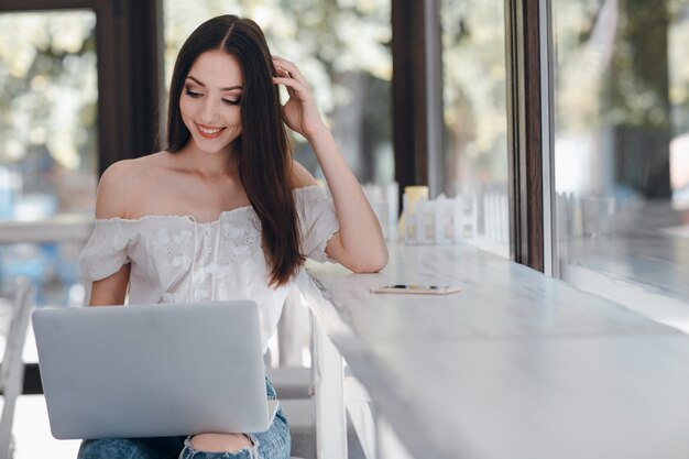 Young girl smiling looking at a laptop holding on her legs