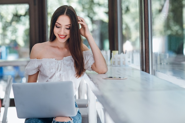 Young girl smiling looking at a laptop holding on her legs