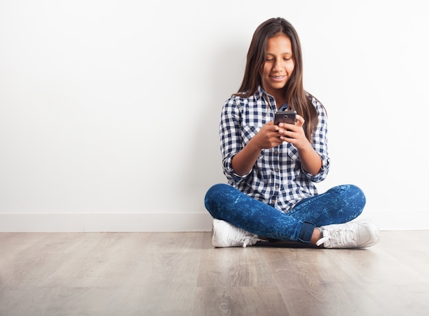 Young girl smiling sitting on the floor with a phone