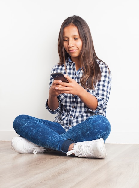 Young girl smiling sitting on the floor with a phone